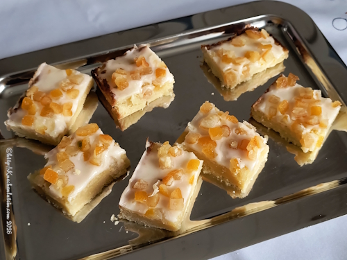 Edelstahltablett mit 7 Tivoli-Keksen, Mürbeteigboden darauf eine Füllung aus Mandeln, Zucker, Butter, Eischnee und Kartoffeln. Darüber eine Puderzuckerglasur mit Orangeat
