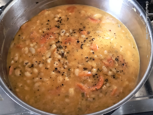 Blick in Topf mit Bohnotto mit Salbei und Karotte