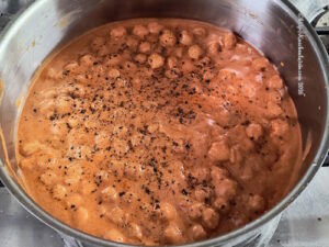 Blick von oben in einen Topf frisch zubereiteter Kichererbsen alla Wodka mit gegrilltem Brokkolini