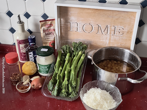 Auf einer Arbeitsplatte sind die Einzelzutaten für Zutaten für Kichererbsen alla Wodka mit gegrilltem Brokkolini aufgebaut
