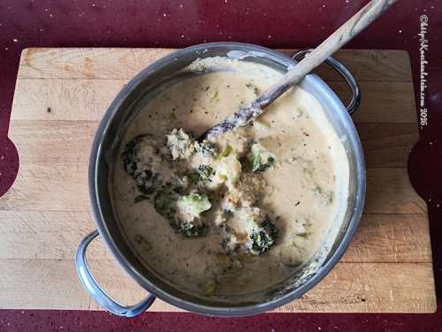 Topf mit Brokkoli-Cheddar-Suppe in der ein Kochlöffel steckt