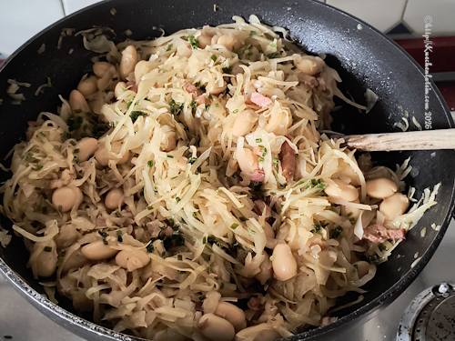Kraut-Ponzker, geschmortes Weißkraut mit Zwiebeln Speck und Riesenbohnen in einer Wokpfanne