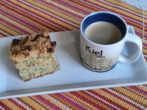 1 Stück Orangen-Ricotta-Mohn-Kaffee-Kuchen neben gefüllter Kaffeetasse